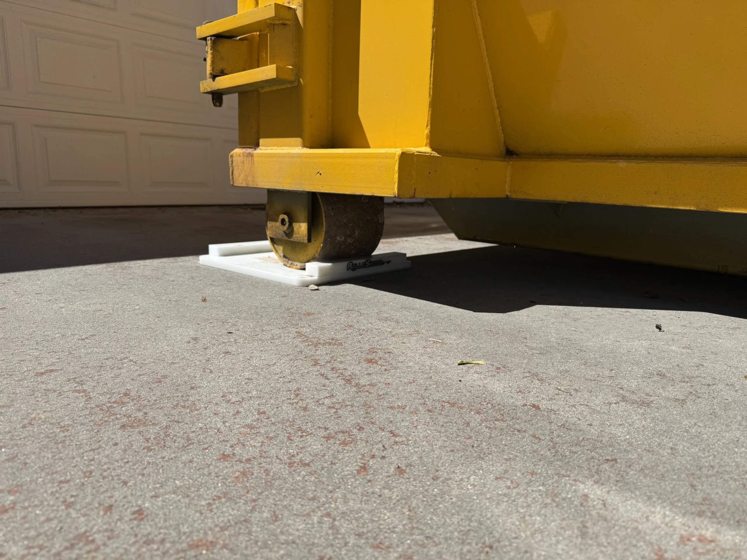 Close-up of the RolliSkate protective roller between the dumpster and the driveway